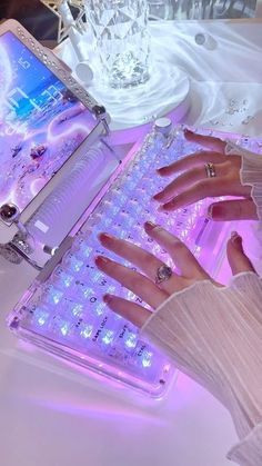 a woman's hands on a keyboard in front of a laptop computer with glowing lights