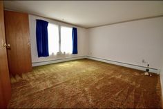 an empty room with carpet and blue curtains