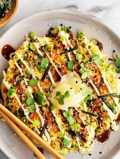 a plate topped with rice and vegetables next to chopsticks