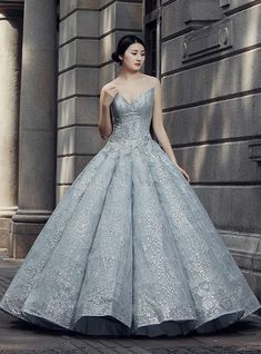 a woman in a silver ball gown standing on the street with her hands behind her back