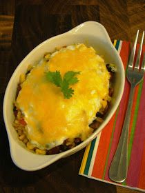 a casserole dish with meat and vegetables on a striped placemat next to a fork