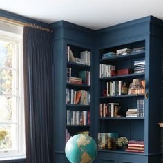 a living room with blue bookshelves and a globe