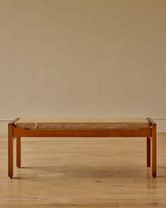 a wooden bench sitting on top of a hard wood floor next to a white wall