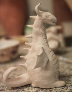 a white ceramic dragon sitting on top of a counter