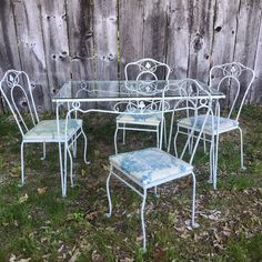 an old table and chairs are sitting in the grass