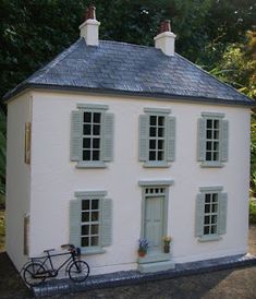 a white house with blue shutters and a bicycle parked in front