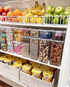 the shelves are filled with different types of snacks and fruit in plastic bins on them