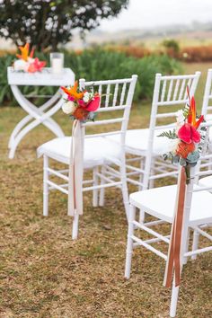 white chairs with orange and red flowers on them are set up for an outdoor ceremony