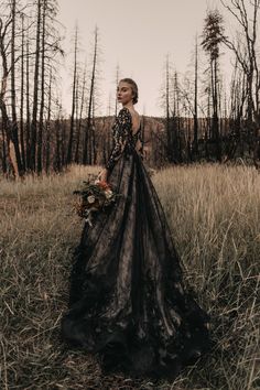 a woman standing in a field wearing a black dress