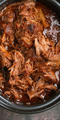 shredded meat in a slow cooker with sauce on the side, ready to be eaten