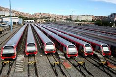 there are many trains that are parked on the train tracks in this photo and one is red