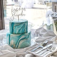 a blue marbled cake sitting on top of a table next to utensils