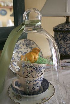 an image of a teacup with a bird in it under a glass dome on a table