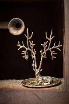 a small metal tree on top of a wooden shelf next to a roll of toilet paper