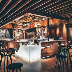 a dimly lit bar with stools and tables in front of an open fire place