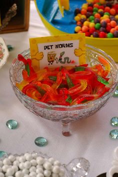 a bowl filled with gummy bears sitting on top of a table next to other candies