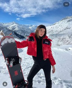 a woman standing in the snow with her snowboard