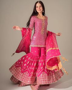 a woman in a pink outfit is posing with her arms out and legs spread wide