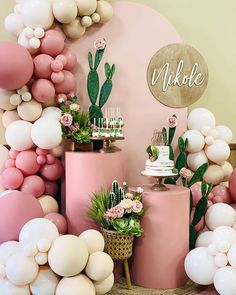 there is a cake and balloons on the table in front of this wall that has succulents, cacti, and other decorations