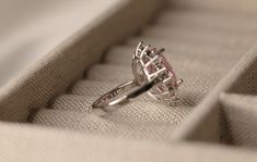 an engagement ring sitting on top of a cushioned box with the lid open to show it's intricate filigree design