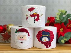 three rolls of toilet paper decorated with santa claus and snowmen