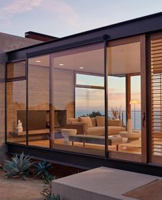 a living room with glass walls overlooking the ocean