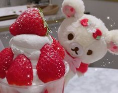 there is a small cup with strawberries in it and a stuffed animal next to it