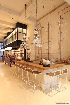 a kitchen with lots of counter space and lights hanging from the ceiling, along with bar stools