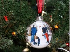 an ornament hanging from a christmas tree decorated with family pictures and red lights