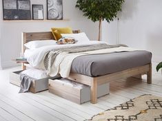 a bed sitting on top of a white wooden floor next to a potted plant