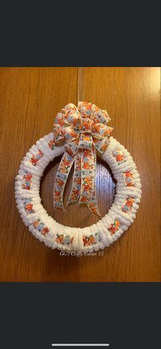 a white wreath with flowers on it sitting on top of a wooden table next to a string