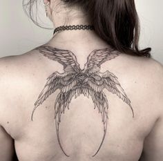 the back of a woman's neck with an angel wing tattoo on her chest