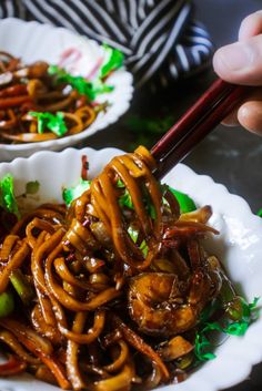 someone is holding chopsticks over noodles in a white bowl with green and red trim