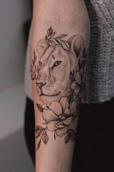 a woman's arm with a lion and flowers tattoo on her left arm,