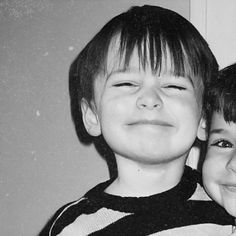 two children are smiling and posing for a black and white photo with their eyes closed