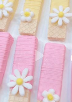 pink and yellow desserts with white flowers on them are arranged in rows next to each other