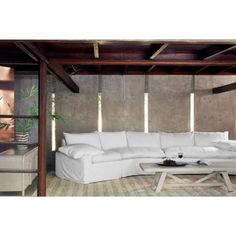 a large white sectional sofa in a living room with wood beams and exposed ceilinging