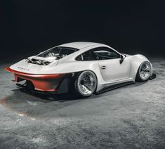 a white and orange sports car parked in a dark room with its hood up on