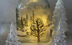 there is a glass bottle with a tree in it and two small trees on the bottom