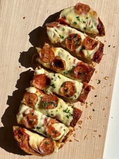 four slices of pizza sitting on top of a wooden cutting board with cheese and pepperoni