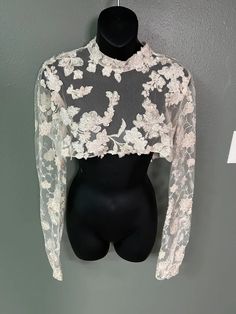 a mannequin wearing a white top with flowers on it's chest and long sleeves