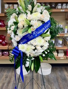 a bouquet of white flowers with blue ribbon on display in a store or flower shop