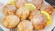 lemon and powdered sugar filled pastries on a white plate with silverware next to it