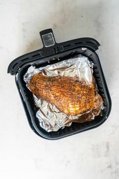 a piece of chicken in foil sitting on top of an air fryer oven pan