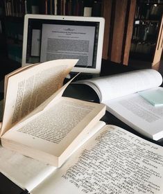 an open book sitting on top of a desk next to a computer monitor and keyboard