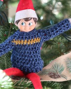 a knitted elf ornament hanging from a christmas tree