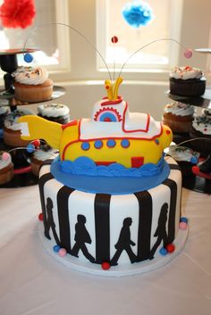 there is a cake that looks like a submarine on top of the table with cupcakes