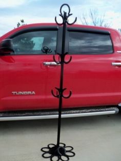 a red truck parked in a parking lot next to a black pole with hooks on it