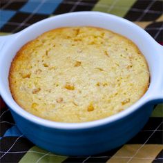 a close up of a cake in a blue bowl on a table with a checkered cloth