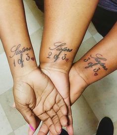 two people are holding hands with tattoos on their arms and the other hand has writing on it